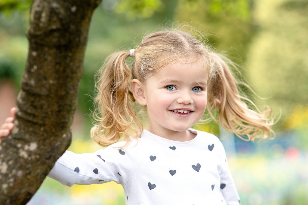 Blue eyed little girl with blonde pigtails wearing a polka heart top