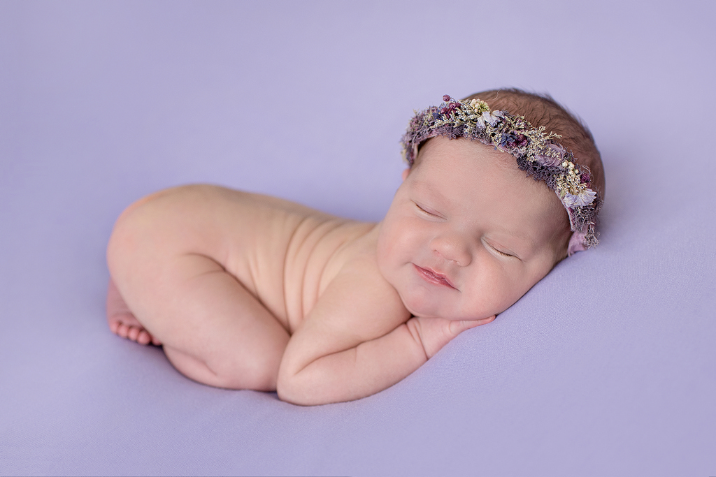 purple background with a newborn baby sleeping