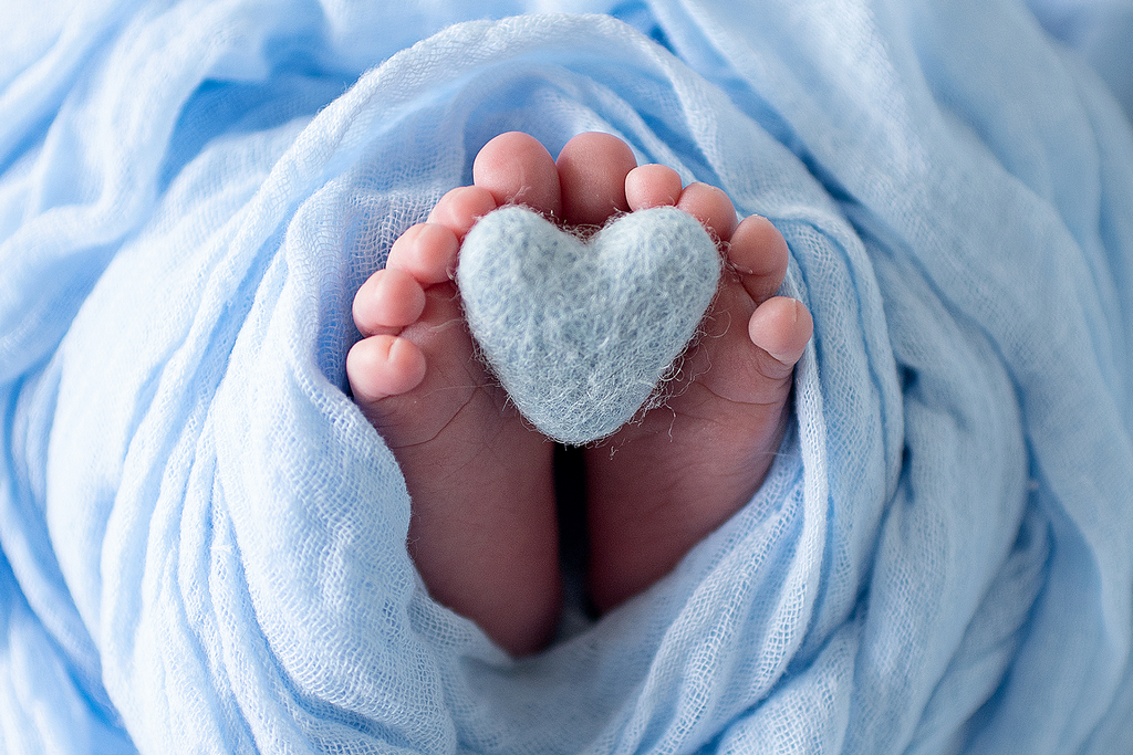 newborn baby feet with a blue fluffy heart - professional newborn photography by Kelly McCambley