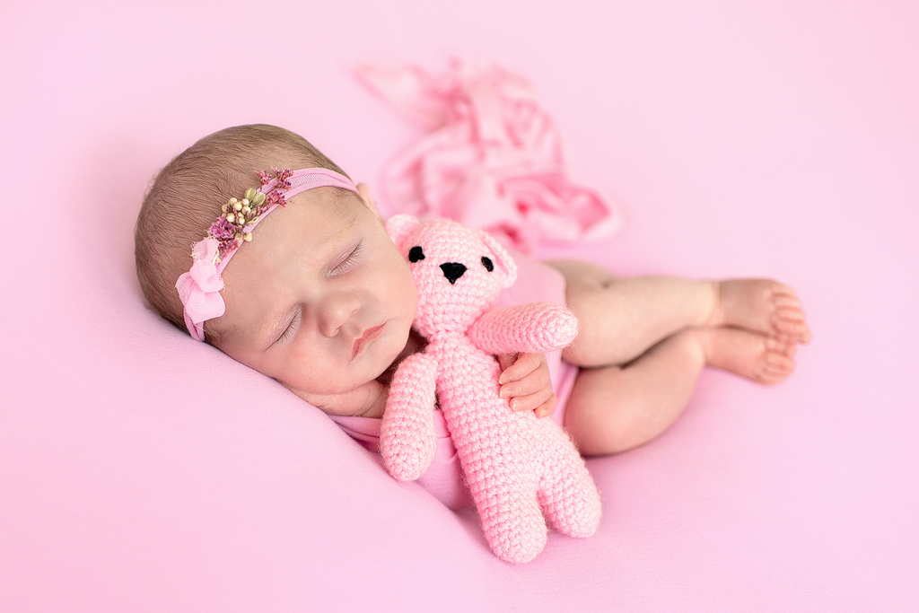 newborn baby girl hugging a teddy bear