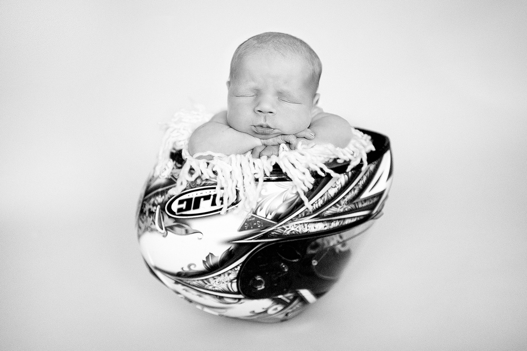 newborn asleep in a motorbike helmet - professional newborn photography by Kelly McCambley