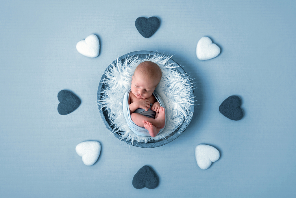 newborn sleeping in bowl surrounded by hearts - - professional newborn photography by Kelly McCambley
